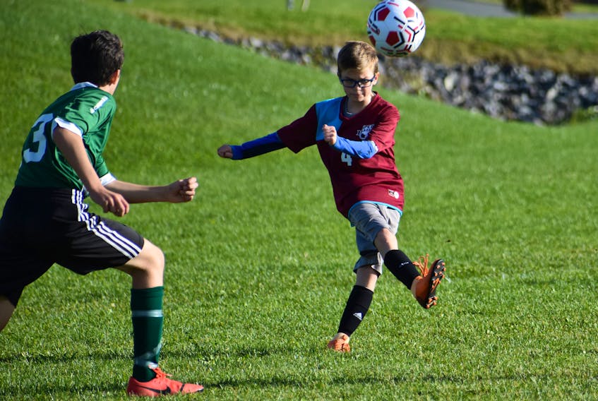 Cole Hutchison-Mills of Sherwood Park Education Centre, right, kicks of the ball as Parker MacSween of Breton Education Centre pressures during Cape Breton Middle School Soccer League action at Open Hearth Park grass field in Sydney on Friday. The game finished tied 2-2.