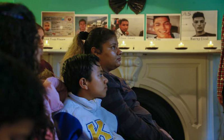 About two dozen people took part in a community gathering at the Glitter Bean Cafe in Halifax on Saturday to express their solidarity with the caravans of refugees and migrants currently en route to the U.S.-Mexico border. On the mantle in the background are photos of some of the young men who have died on the journey.