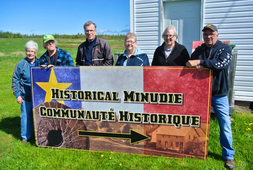 (From left) Sharon Gould, Jim Hamilton, David Milner, Sylvia McCoy, Jackie Theal and Dara Legere stand behind one of the new Welcome to Minudie signs that have been erected in the community that overlooks the Cumberland Basin and the River Hebert River. The signs showcase the community’s Acadian heritage, while also celebrating the grindstones that Amos ‘King’ Seaman shipped from an area quarry to the United States.
