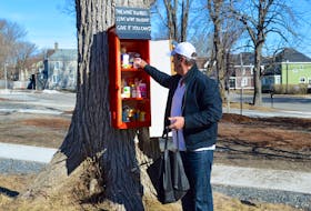 During an Easter Sunday stroll, Sydney resident Alan Fagan places a few donations in a mystery cupboard that recently appeared on a tree in the community's historic north end near the corner of Nepean and George streets. A sign over the pair of anonymously set-up cupboards reads “Take what you need. Leave what you don’t. Give if you can.”
