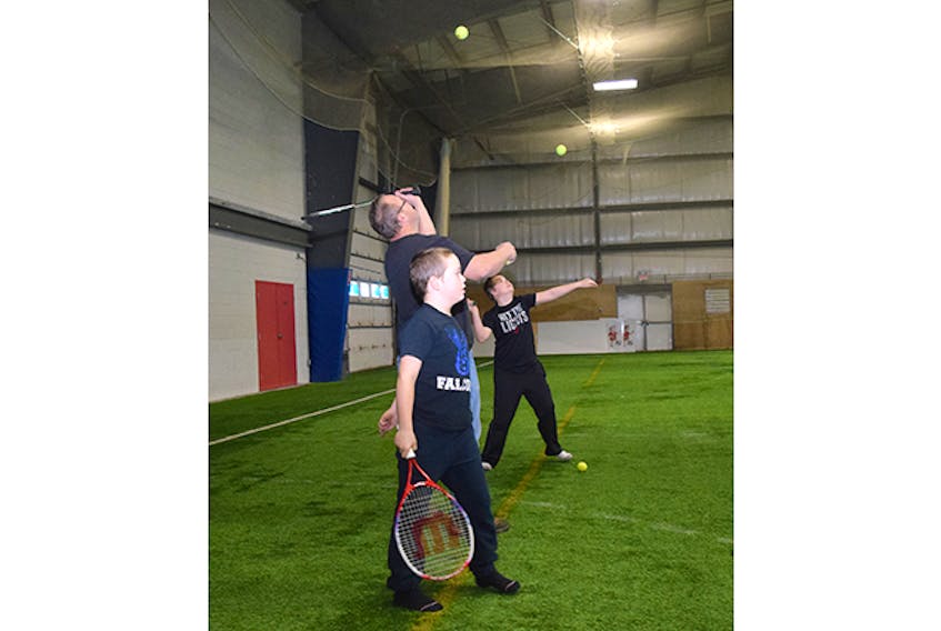 Liam Ross, of Stellarton, shown at left along with his dad Craig and brother Bryan, hits a few balls on the indoor tennis courts at the sports facility in Stellarton on Tuesday.