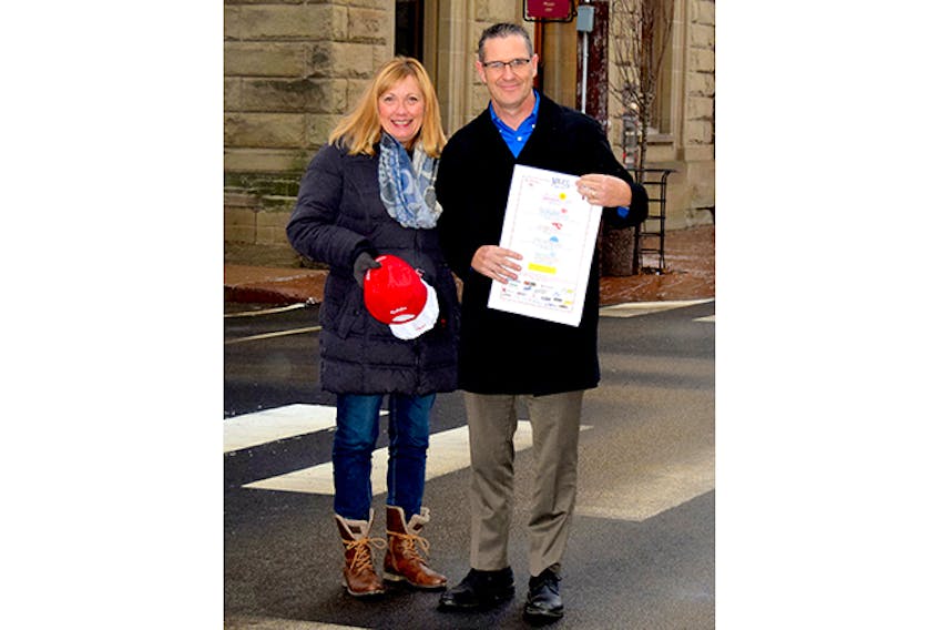 Terry Curley, race director of the Johnny Miles Running Event Weekend, shares the news about a registration fee reduction for 2018 with New Glasgow Mayor Nancy Dicks as the two pose at the start/finish line of the event on Provost Street in downtown New Glasgow. (Photo by Kimberly Dickson)
