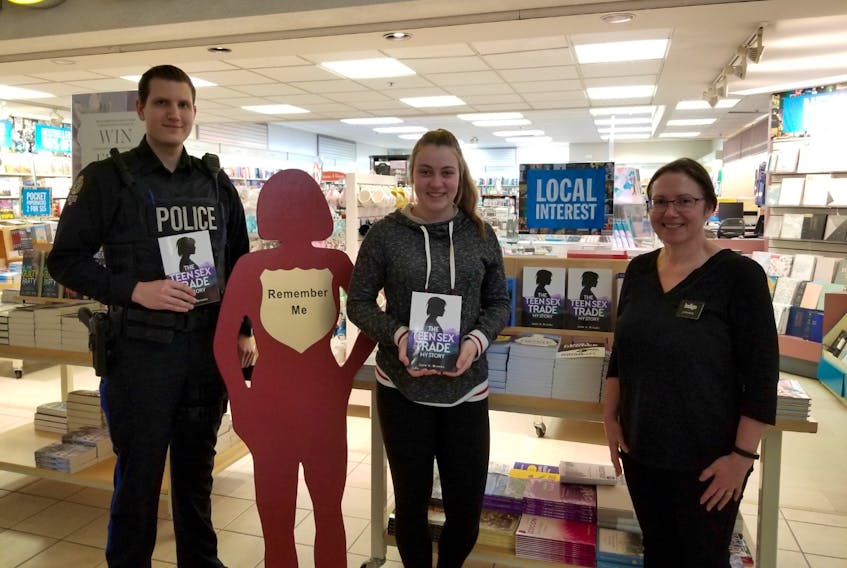 Const. Kyle Waters of the New Glasgow Regional Police, Pictou Academy student Jenna Reid and Joanna Mason hold copies of Jade Brooks book The Teen Sex Trade, My Story, which is available at Coles in the Highland Square Mall. Brooks will be speaking at a conference on human trafficking later this month.