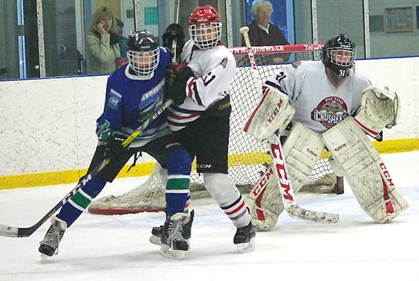 Bantam AA Crushers goalie Xander Vohs sets up as defender Brent Chapman tries to clear the way.