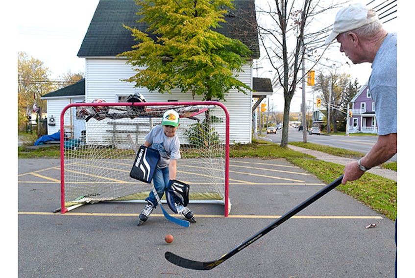 Bernie MacDonald take some shots on his grandson Cohen Ross Wednesday night, in an empty parking lot in New Glasgow.