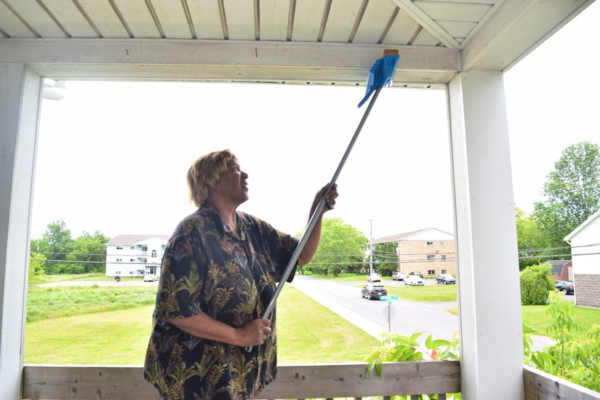 Caroline Bowden cleans under a balcony cover at Woodbine Crest seniors apartments in New Glasgow.