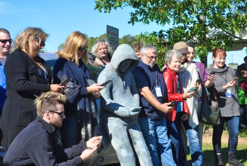 Visitors at the New Glasgow riverfront on Sunday struck a tongue-in-cheek pose with the newest sculpture found by the Glasgow Square Theatre, entitled Chilling by the River.