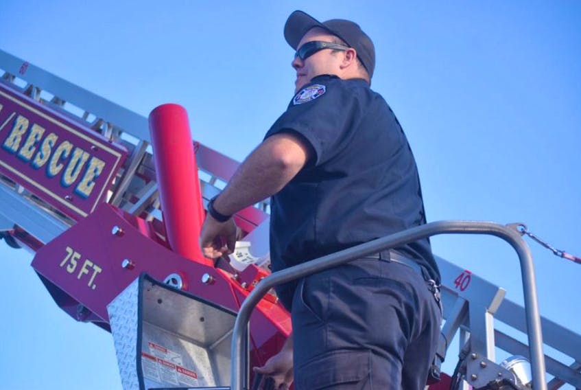 Evan Hale, driver-operator with the New Glasgow Fire Department demonstrates how the ladder work’s on one of the department’s trucks.