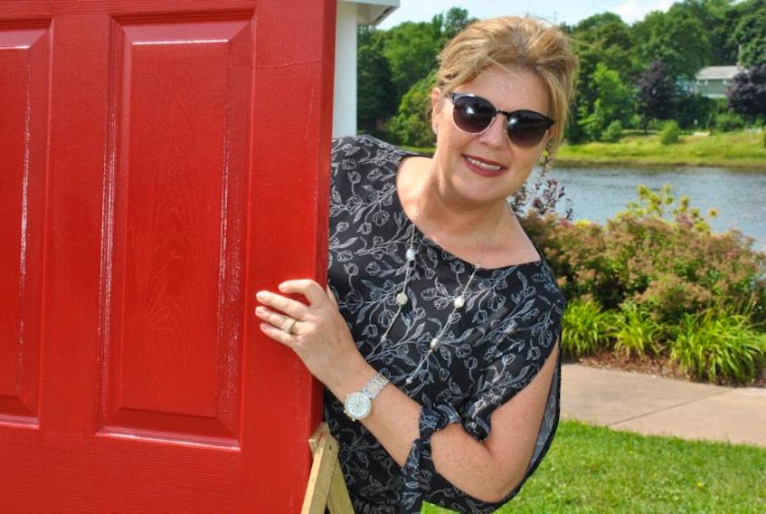 Geralyn MacDonald peeks out from behind a red door that appeared near Glasgow Square on Wednesday morning.