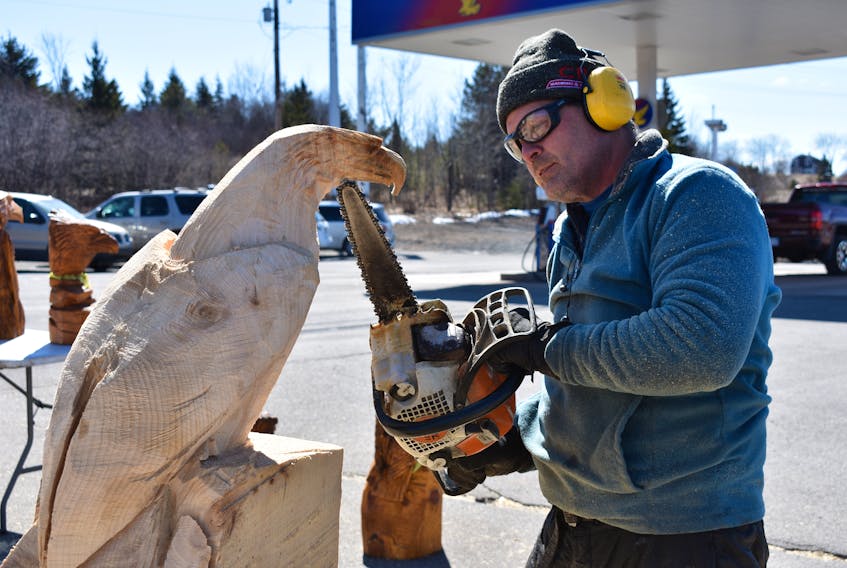 Rob Milner, preparing to hew the image of an eagle out of a hunk of wood, on East River Road. Milner diligently created his eagle carving on Monday – he plans to donate it to the Special Olympics.