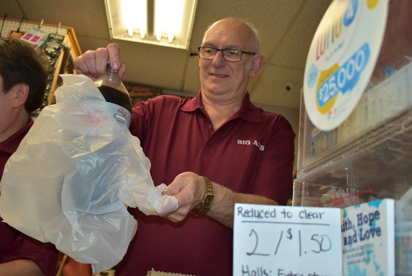 Al Sutherland, owner of Big Al’s convenience bags a customer’s purchase Wednesday at his New Glasgow store.