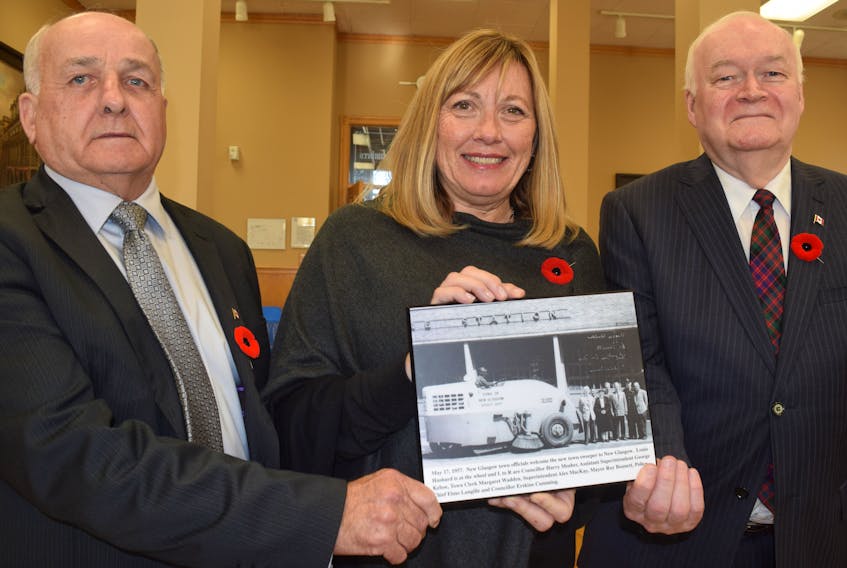 Philip MacKenzie, left, and Clyde Macdonald of the Pictou County Roots Society present New Glasgow Mayor Nancy Dicks with this photo depicting the arrival of a new street sweeper, back in 1957.