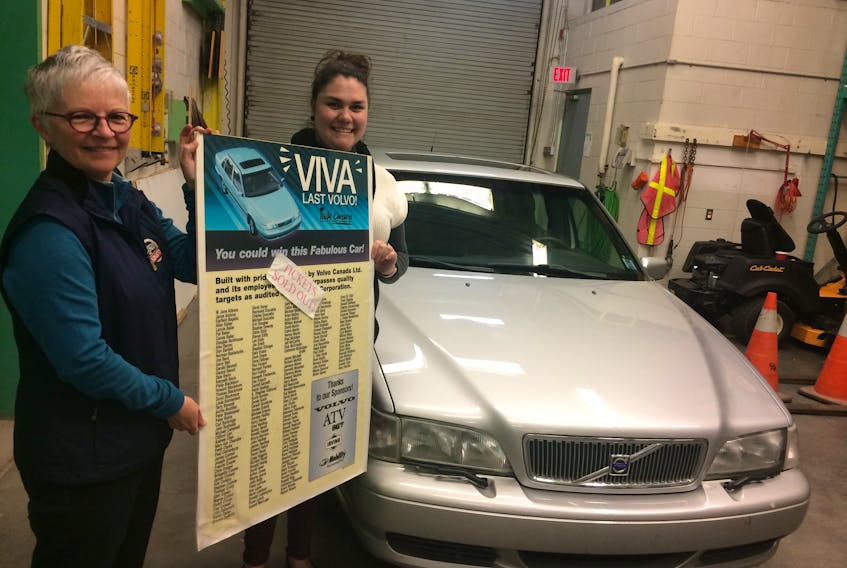 Debra MacNabb, left, director of the Nova Scotia Museum of Industry, and Erika Smith, curator of collections, hold a poster that was on display when the 1999 Volvo S70 was raffled off by the IWK-Grace hospital as fundraiser. The Volvo is the last of the cars manufactured in Canada and was recently donated to the Museum of Industry.