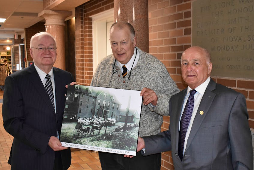 Clyde Macdonald, left, and Philip MacKenzie, right, present Dr. James MacLachlan with a photo of a graduating class of nurses at the old Aberdeen Hospital.