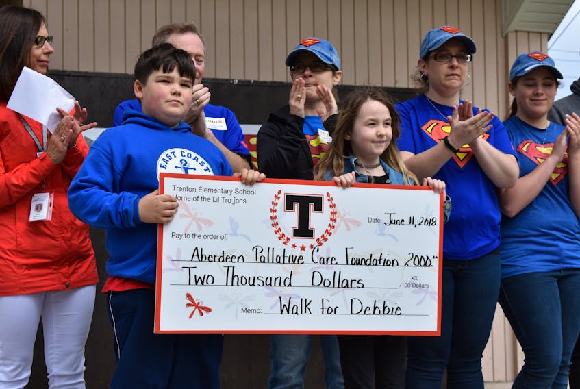 Mattie Davis, and Erin Farrell – two Trenton students who have fought cancer and won – proudly display the $2,000 raised on behalf of Debbie Campbell on Monday morning in Trenton Park. Looking on are members of the Campbell family (in blue), and Bonnie McCarron, a cancer patient navigator with the Nova Scotia Health Authority.