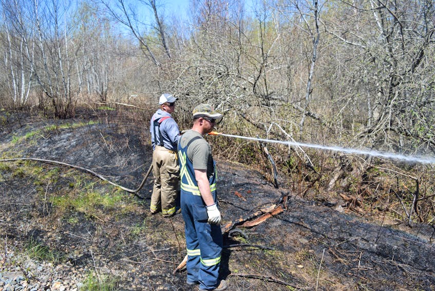 Jarred Campbell of the Stellarton Fire Department and town employee Vince Conway work to put out a small fire near the train tracks in the Brown Row area on Monday afternoon.