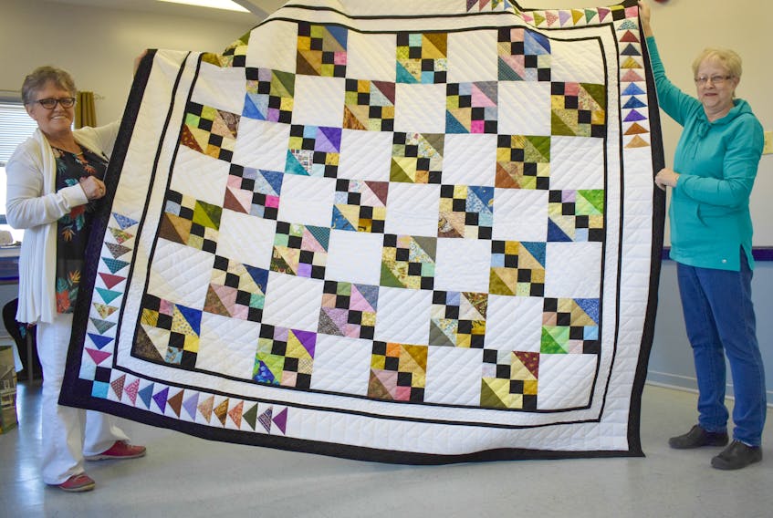 Quilters Debra Battist, left, and Joan Watters display the ‘Flying Four Patch’ quilt in Westville on Wednesday.