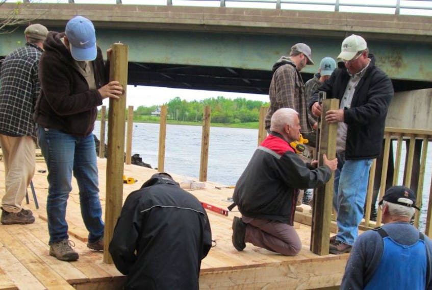 Volunteers are shown building the deck along the waterfront at Bissell Park.