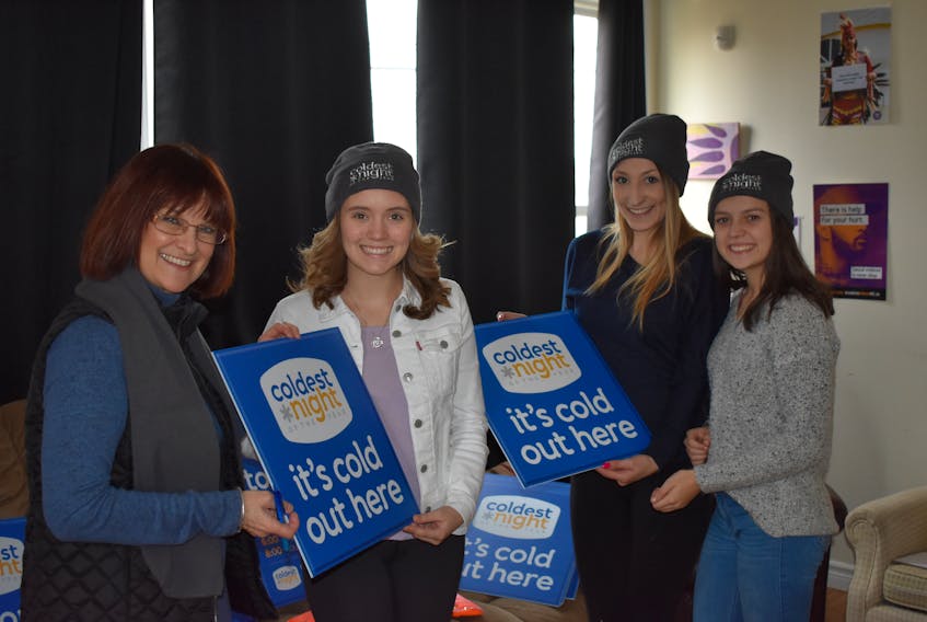 Jan Keefe, event director for the 2018 Coldest Night of the Year, left, and youth worker Shayla Gorman, second from right, present signs and hats for the upcoming community event to two Grade 12 volunteers, Abbie Delaney, second from left and Lucia MacKay who will be helping out with this weekend’s event.