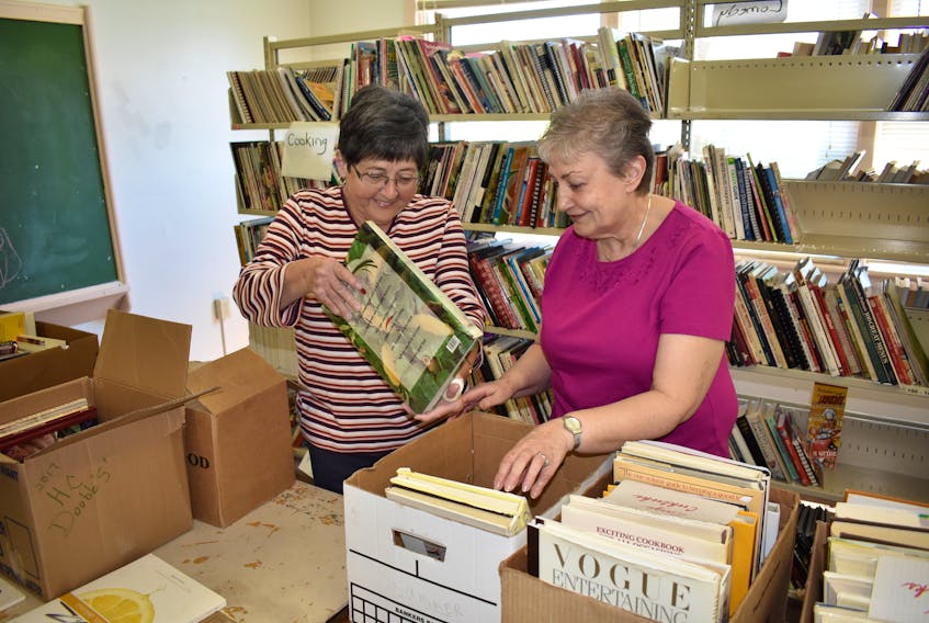 Marie Benjamin and Cathy Murphy, members of the Our Lady of Lourdes Catholic Women’s League (CWL) prepare a variety of books for sale.
