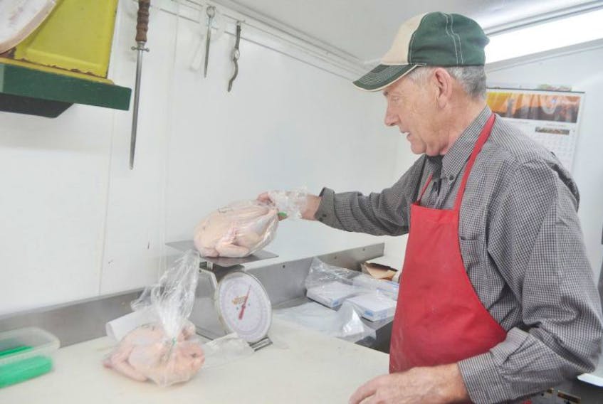 Gordon Fraser weighs a chicken at his butcher shop in Millbrook, Pictou County, in this file photo. After struggling to get insurance for his property, he made the decision to close after 39 years in operation.