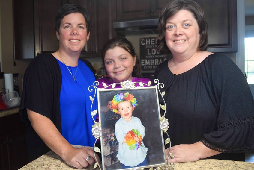 Jodi MacIvor, Hannah MacIvor and Hayley Finley, with a photo of Molly taken less than two weeks before she died.