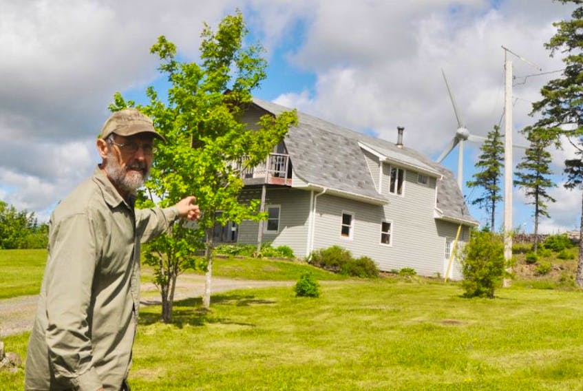 Ward Brubacher stands by a neighbour’s house which has a large wind turbine located close by.