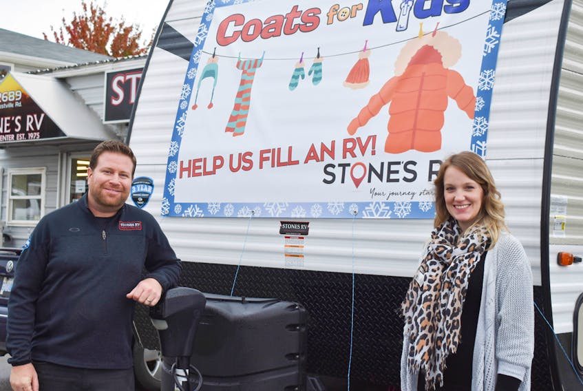 Jonathan Stone, owner of Stones RV and Catherine Millen, marketing coordinator for the company stand beside an RV they hope to fill with donations for Coats for Kids.