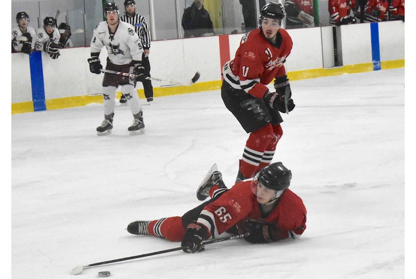 Robert Burrows of the Pictou County Scotians tries to hang onto the puck while falling to the ice in a Nova Scotia Junior Hockey League game played on Sunday in Trenton. Looking on is Scotians forward Morgan Timmons.