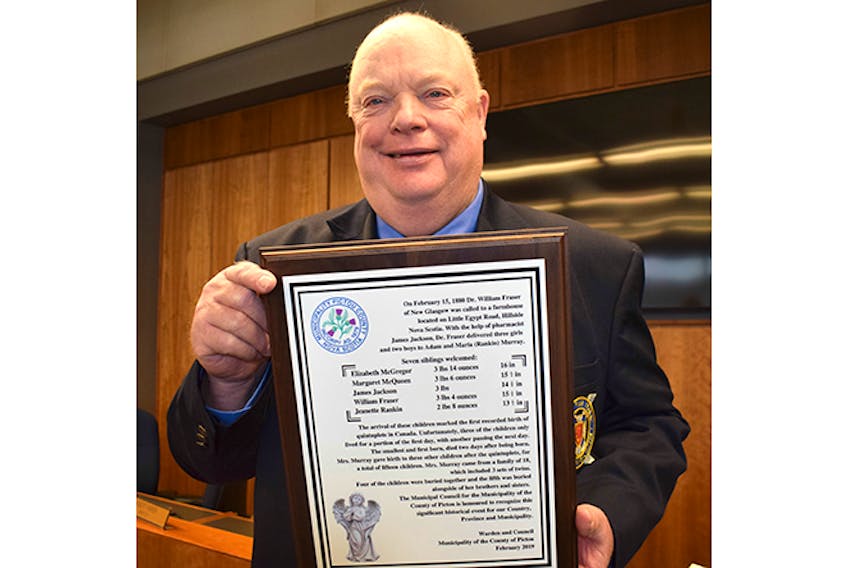County councilor Peter Boyles displays a plaque about the Murray quintuplets, born in Hillside, Pictou County in 1880.