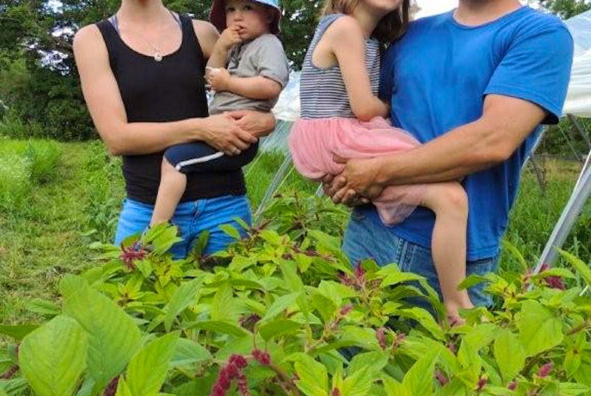 Niki Allan and James Kaloc stand amid their flower garden with youngest children, Theodore, left, and Aven, on their farm property in Rocklin, 15 minutes from Westville.