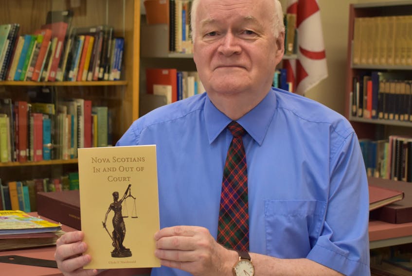 Clyde Macdonald holds a copy of his latest book, Nova Scotians In and Out of Court.