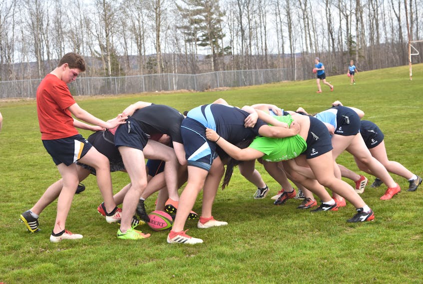 A group of players with the boys and girls rugby teams at NNEC practice a scrum drill on May 6.