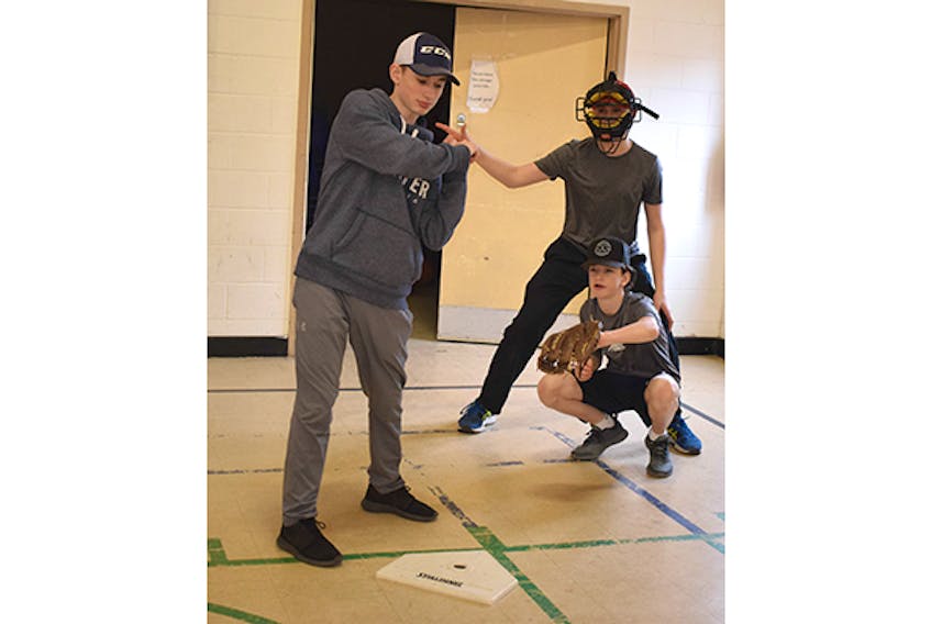 Cale Archibald works behind the plate during an umpiring clinic held on April 27. Also shown are Ben MacGillivray (simulating a hitter) and Cory MacGillivray.