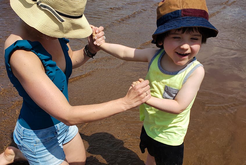 Jennifer Broadbent holds her son Obie’s hands as he stands in the water at Pasadena Beach on Sunday. The Corner Brook family used the newly installed Mobi-Mat to get Obie’s wheelchair down to the water’s edge.