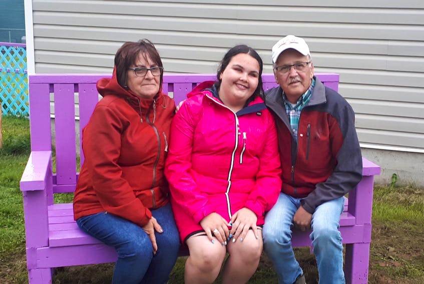 The family of the late Tammy Parsons is seated at the new buddy bench outside the St. Vincent de Paul Food Bank in Carbonear. From left are Tammy's mother Debbie Parsons, daughter Brianna and father Dave Parsons.