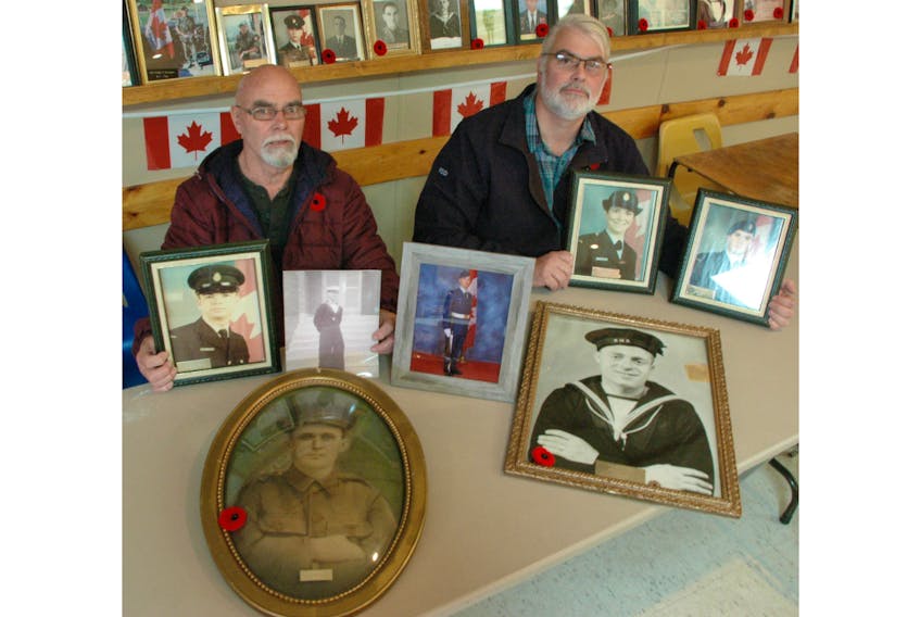 At the St. Anthony Royal Canadian Legion Branch 17, Levi (Dick) Reid and son Rick Reid present photos of all seven family members who have served the military. In the foreground are pictures of the first Levi Reid, who served in the First World War; and Levi "Lev" Reid who served in the Second World War. Dick holds pictures of his son Tracy and himself. In the centre is a picture of his grandson Vincent. Meanwhile, Rick holds a picture of his sister Dawn and a picture of himself. STEPHEN ROBERTS/THE NORTHERN PEN
