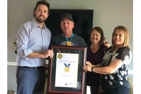 Andrew Parsons, left, presents Bill Wagg with the Newfoundland and Labrador Award for Bravery as Wagg's wife Claudine and friend Tammy Farrell, who nominated Wagg for the award, look on.