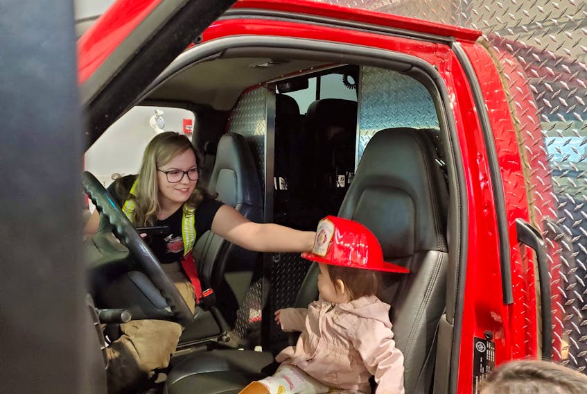 Fayth Shroeder, one of three women who volunteer with Deer Lake Fire Rescue, has some fun with an unidentified child during a recent tour of the fire department’s premises.