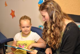 Gordina Barnes, left, reads a book with Cecilia Loder, her Summer Reading for Fun tutor, at the Family Outreach Resource Centre site in Corner Brook.