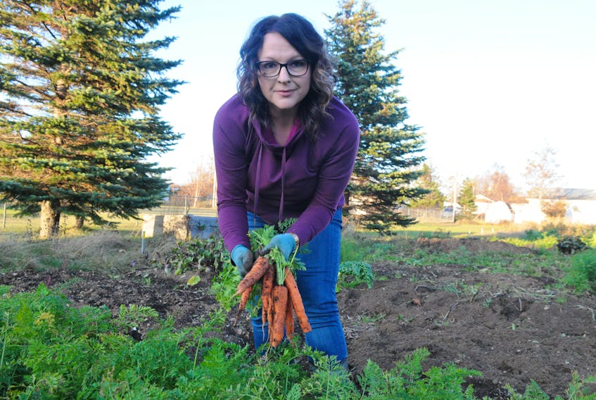 Carla Sharpe of Stephenville displays some of the carrots she harvested from one of her plots at the community garden in Stephenville.