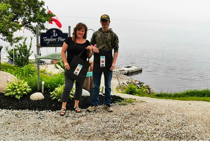 Woody Point’s events co-ordinator Paula Alexander, left, and student employee Toby Foss are seen with some of the reusable shopping bags the towns of Woody Point, Glenburnie-Birchy Head-Shoal Brook and Trout River are giving to their residents.