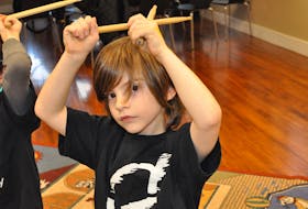 Jude Jenkins lifts his drumsticks above his head in preparation for the cue to start drumming during a recent session of bucket drumming at The Graham Academy in Corner Brook.