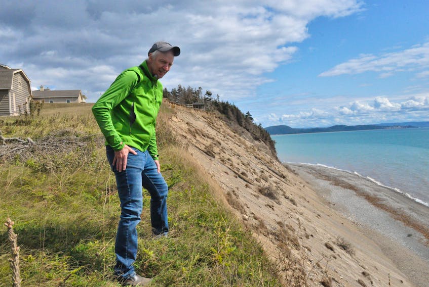 Graham Oliver of the Bay St. George Climate Action Network looks down at some of the coastal erosion near Marine Drive in Kippens, where landowners have lost property due to the bank foundering behind their homes. FRANK GALE/ THE WESTERN STAR