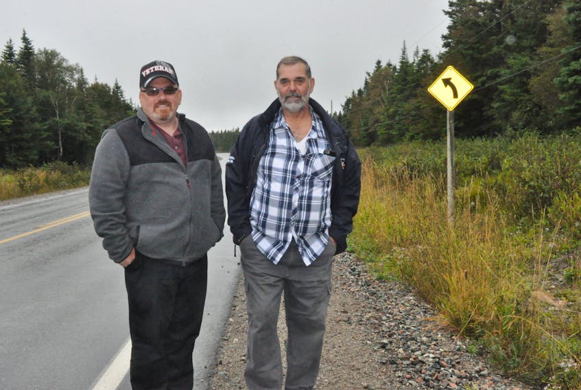 Charlie White, left, and Wayne Alexander, stand on a shoulder of the Hansen Highway in the area where they claim to have seen a large black cat cross the road Sept. 10. FRANK GALE/THE WESTERN STAR