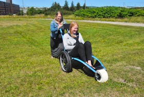 Mary Burt pushes Erin Porter, a fellow summer worker with the Town of Stephenville's Recreation and Wellness Department, as they demonstrate the use of the Hippocampe all-terrain wheelchair recently purchased by the town.