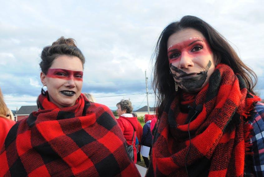 Nicole Lucas, left, with red makeup representing a mask and Tracy McIsaac, wearing the same type of makeup and a black hand painted on her face over her mouth, representing how some women are silenced by men, took part in the peaceful rally in Stephenville on Friday evening to protest Robert Hilroy Legge, the man who murdered Ann Lucas 16 years ago, returning to Stephenville. FRANK GALE/ THE WESTERN STAR