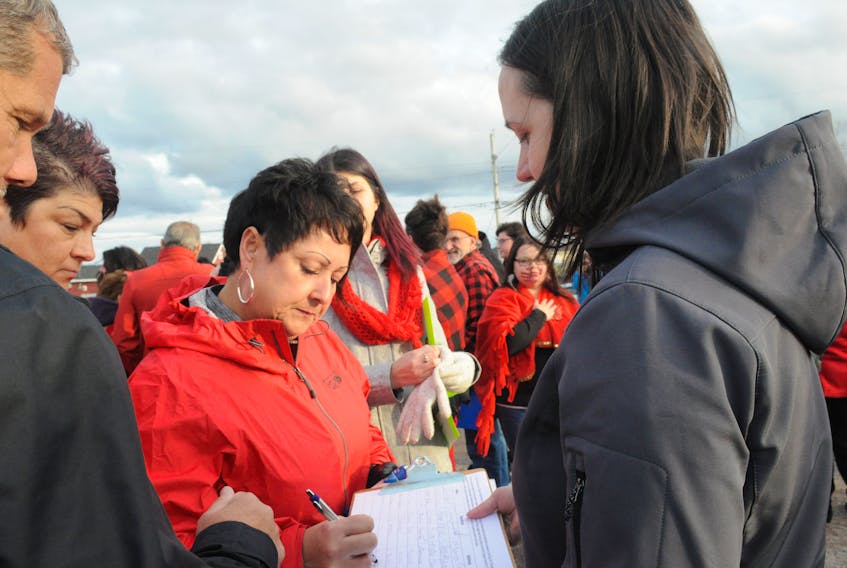 Amanda Russell, left, signs a petition circulated at Friday night's rally by Janice Kennedy, right, executive director of the Bay St. George Women’s Centre. Rally participants were protesting the return to Stephenville of Robert Hilroy Legge, the man who murdered Ann Lucas 16 years ago. FRANK GALE/ THE WESTERN STAR