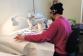 Textile artist and curator Bruno Vinhas, alumni of CNA’s textiles: craft and apparel design program, works on sewing a medical gown as part of the college’s efforts to help meet the province’s needs during the COVID-19 pandemic.
