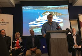 Peter Woodward, CEO of Labrador Marine Inc., speaks at an event in Happy Valley-Goose Bay to announce two new ferries for the north coast of Labrador and the Strait of Belle Isle. Behind him is a picture of one of the two vessels.